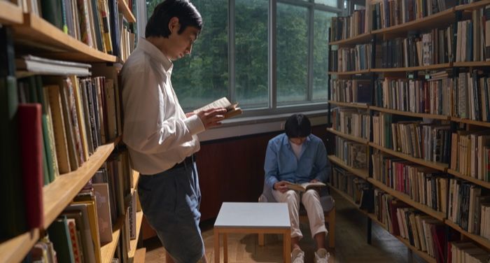 two lighter-skinned men of color readig in a library