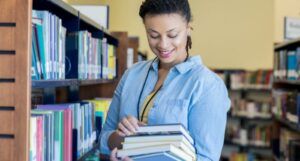 light-skinned bLack woman librarian holding a stack of books