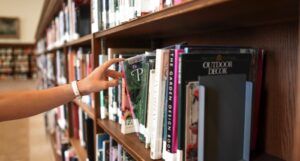 fair-skinned hand reaching for a book in a library