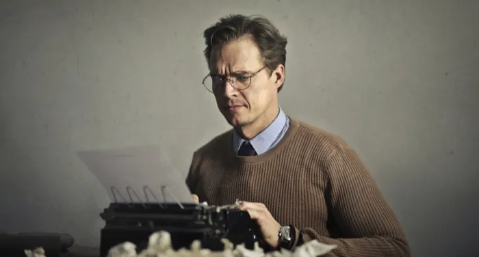 white man typing on an older typewriter
