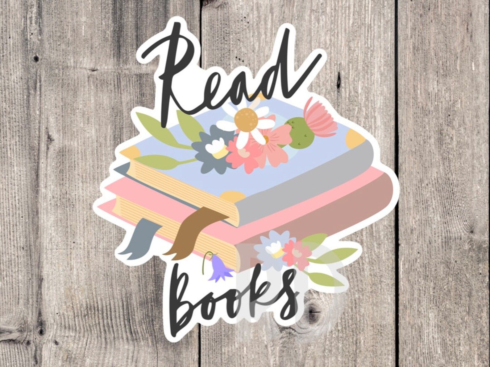 A sticker of a stack of colorful books with flowers on top, and the words Read Books in a cursive script.