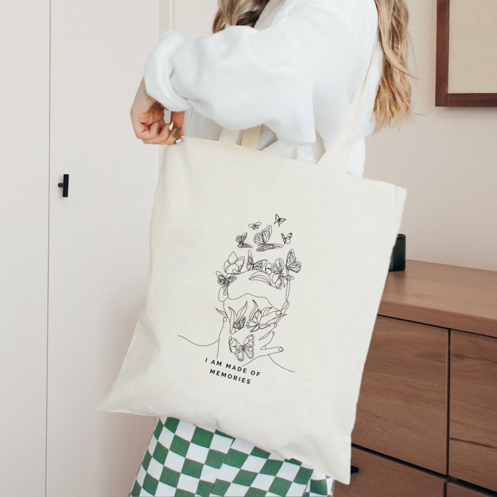 cream tote with black text that reads  "I am made of memories" beneath a line drawing of a person looking up as butterflies surround their face