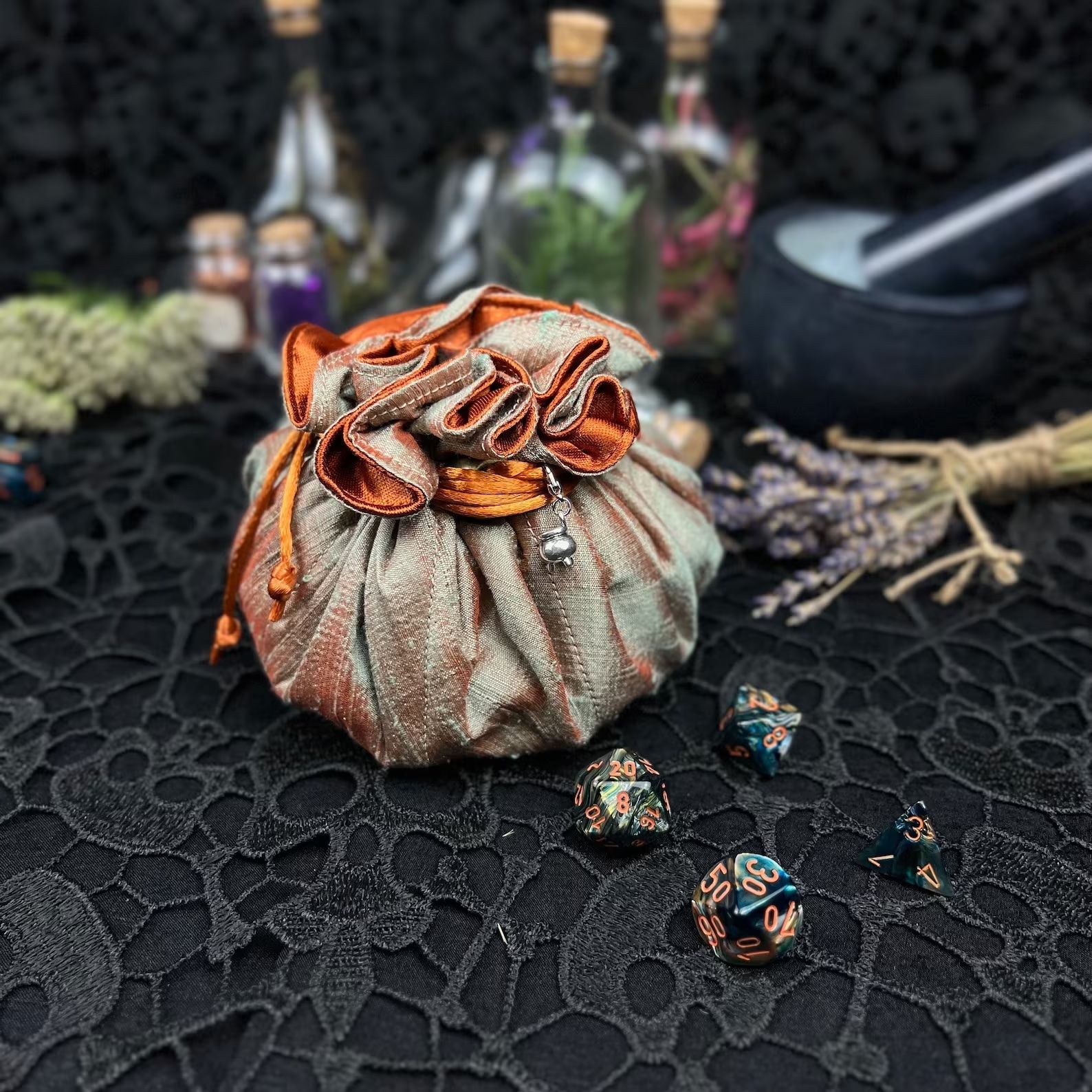 Fabric drawstring bag on a table with jars, herbs, and dice. 