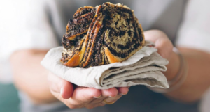 a cropped cover of Now for Something Sweet showing someone holding out a pastry on a folded napkin