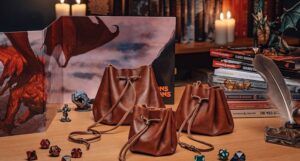three leather dice bags on a table with dice, dnd books, and candles.