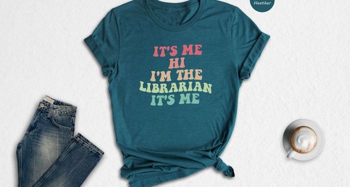 T-shirt with retro rainbow colored text reading "It's me Hi I'm the librarian it's me"