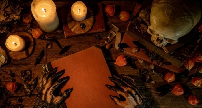 Image of a book with scary hands, candles, and a skull