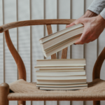 a photo of someone putting a stack of books on a chair