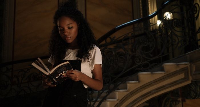 brown-skinned Black woman reading on a staircase