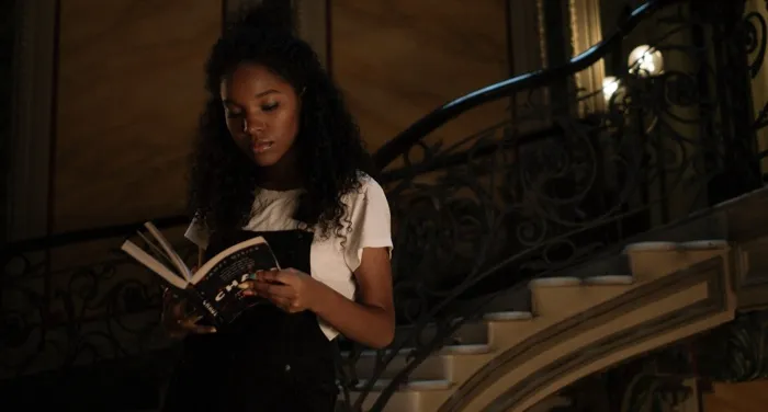 brown-skinned Black woman reading on a staircase