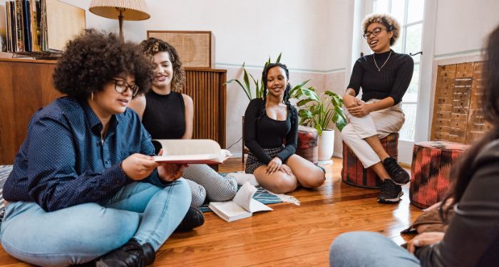 five young women seated in a circle holding books