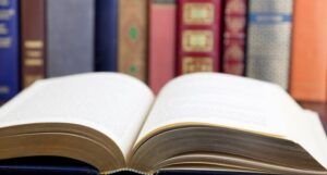 a book open in front of other books lined up alongside each other