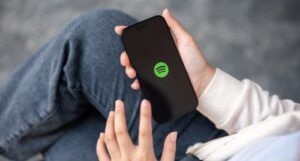 hands holding a cell phone loading the Spotify application