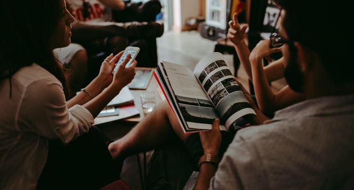 a group of people sitting around each other with books in a dimly-lit room