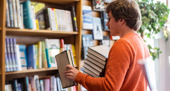 a photo of a man with light skin stocking bookshelves