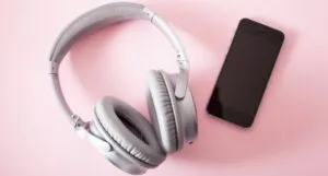 Image of headphones and a phone on aa pink background