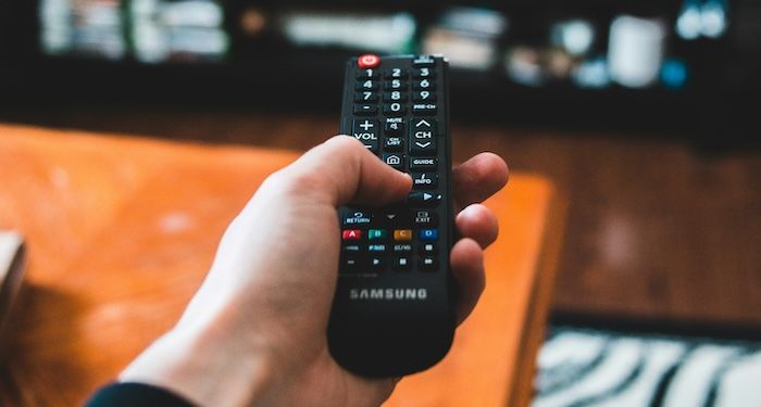 a hand holding a TV remote