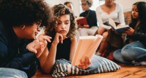 a group of women of different skin tones and hair textures sitting and reading, discussing books