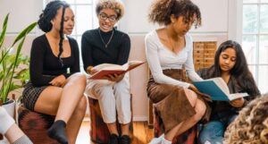 four women of color of various skin tones reading books with each other