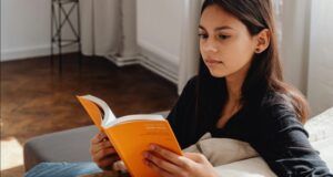 light skinned woman of color reading a book on the couch