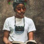 brown-skinned Black woman reading with a camera around her neck