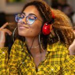 light-skinned Black woman listening to her headphones in a restaurant