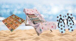 a bookish cornhole set, a chair with a book-print beach towel, and sandals in a bookish print against a blurred beach background