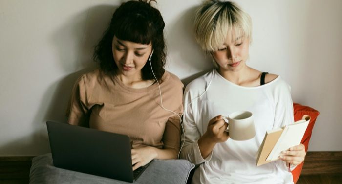 two fair-skinned Asian women reading next to each other