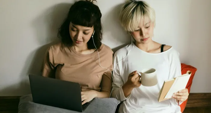 two fair-skinned Asian women reading next to each other