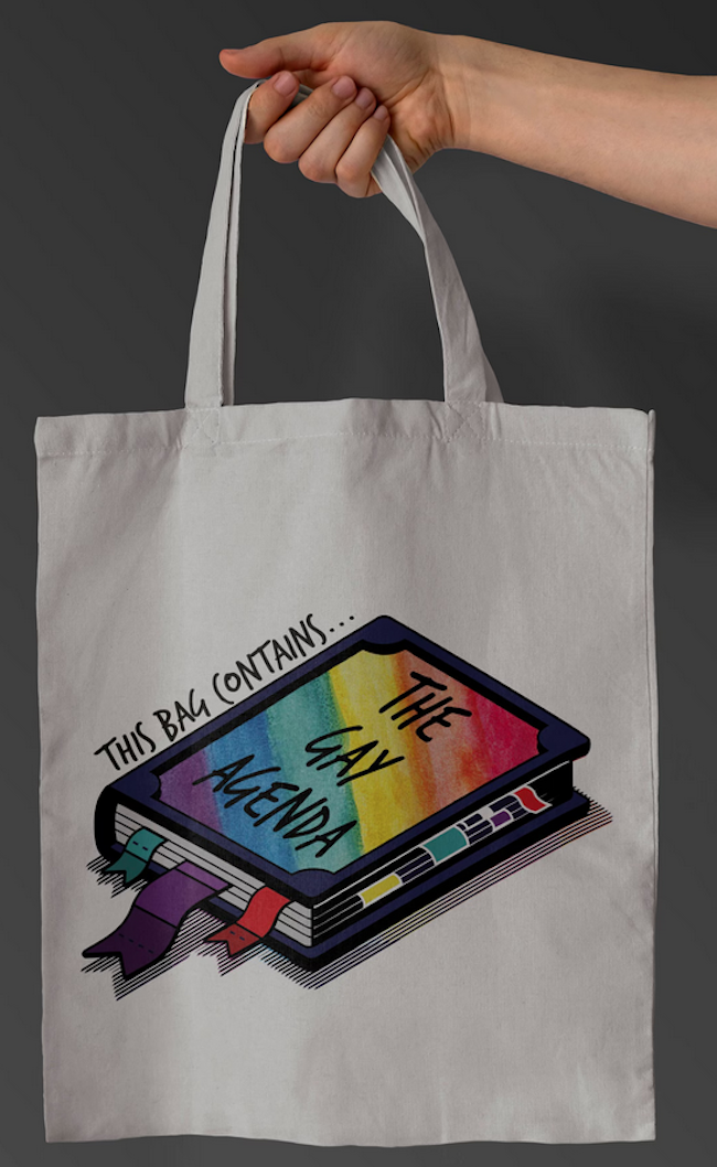 a tote bag with an illustration of a rainbow colored book that says the gay agenda