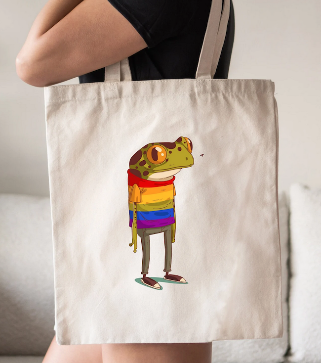 tote bag with an illustration of a frog standing like a person in a rainbow colored sweater