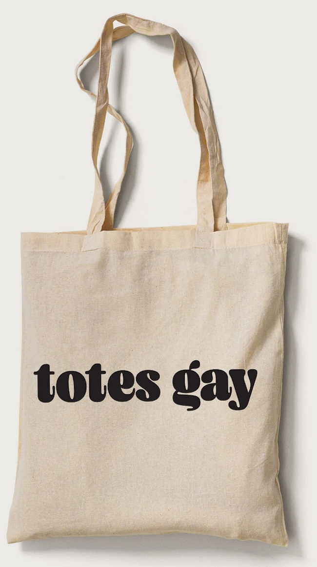 a beige tote bag with "totes gay" printed in black letters