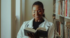 a brown-Skinned Black woman reading and smiling in a library