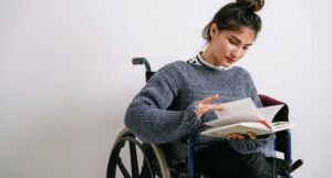 fair-skinned woman in a wheelchair reading a books