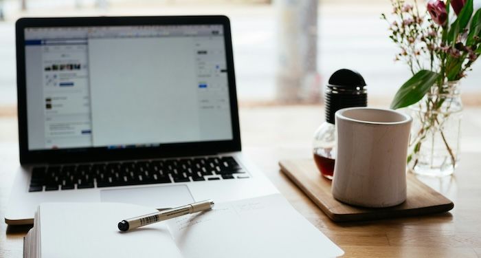 a laptop with notebook and coffee cup