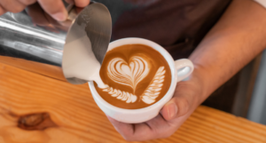 a coffee shop employee pouring a heart as latte art