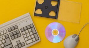 1990s retro technology: an old keyboard, a CD disc and case, and an old computer mouse