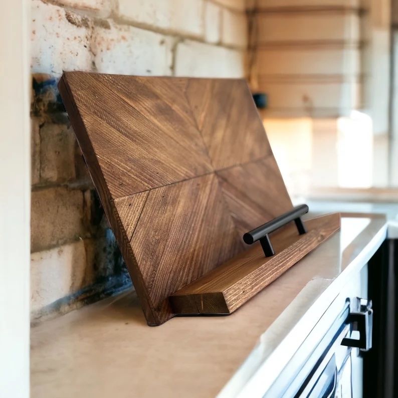 a photo of a wooden cookbook stand with a black metal bar on the front the holds the books