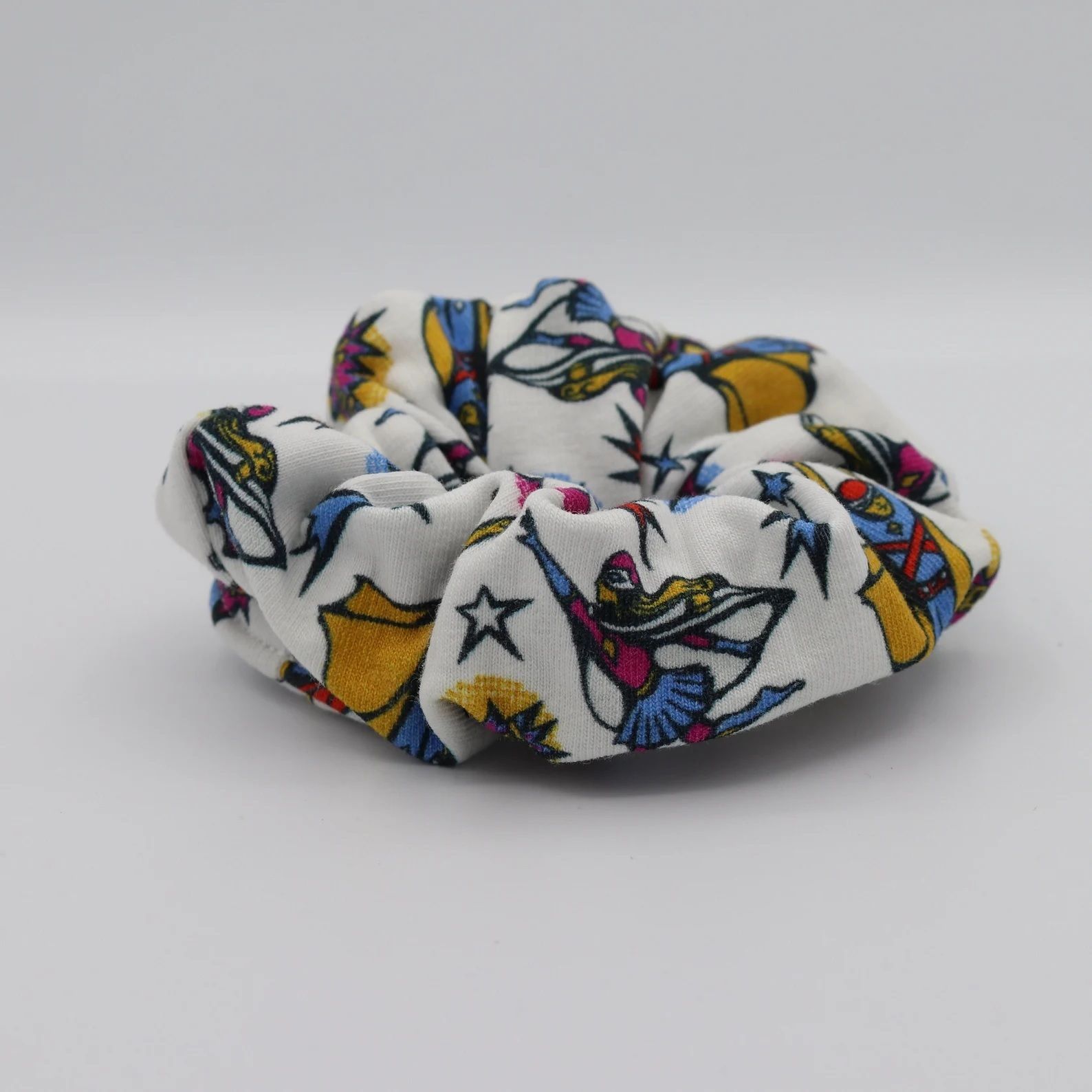 A white scrunchie patterned with superheroes and stars