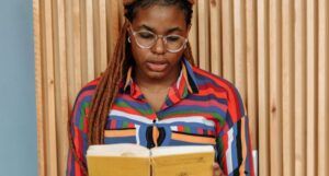 a brown-skinned Black woman with braids reading