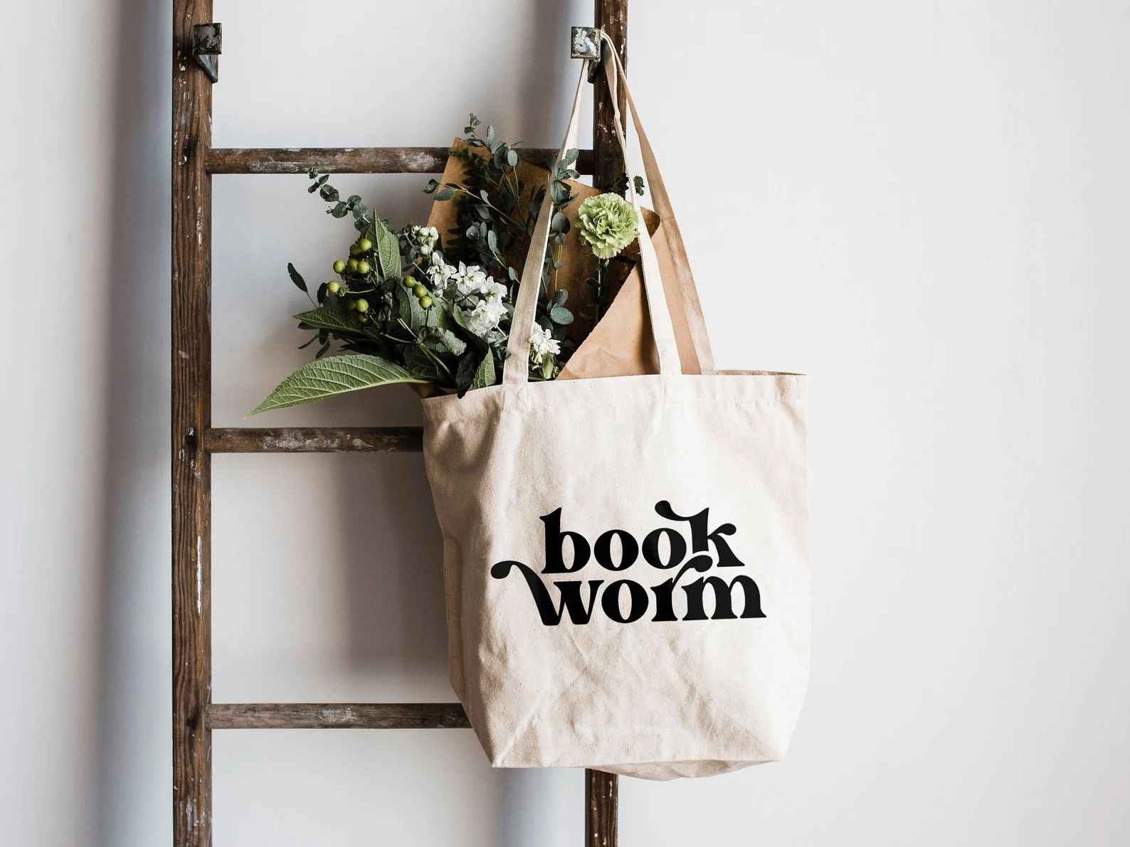 a photo of an off white tote bag with the word bookworm on it