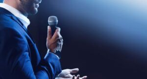 profile of a man speaking into a microphone on stage