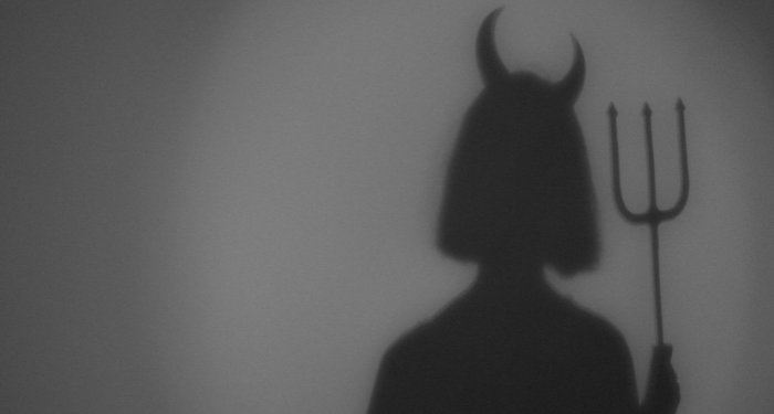 a shadow of a figure wearing devil horns