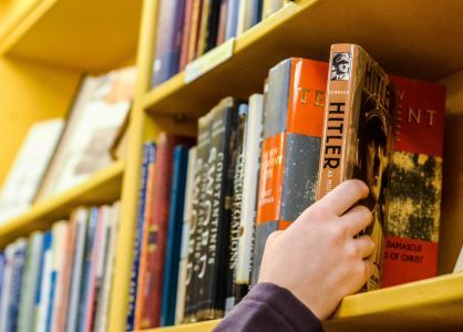 a person's hand browsing books about Hitler