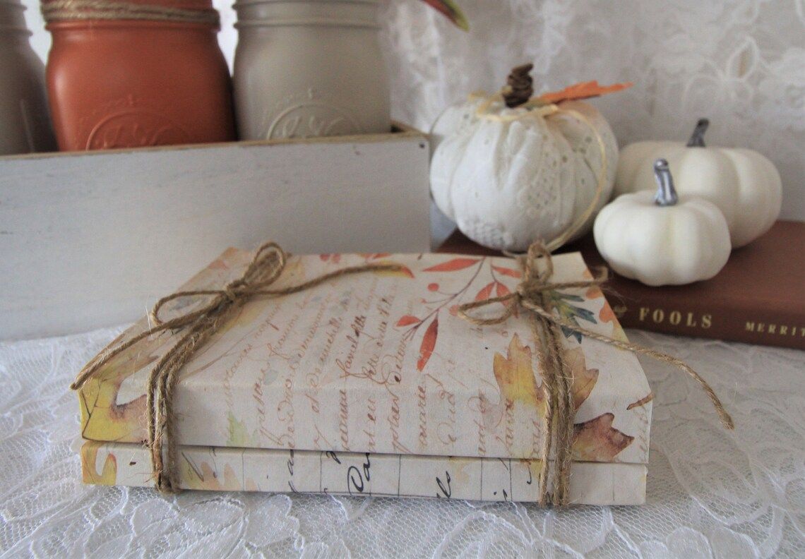 Two books covered in autumn leaves print paper and tied with twine