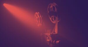 film reels on an old projector with a black and dark red filter applied to the image