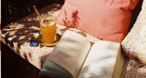 open book with iced tea on a summery outdoor couch