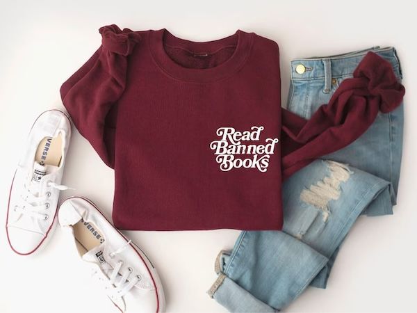 dark red crewneck sweater with white text in the upper left that reads "Read banned books"