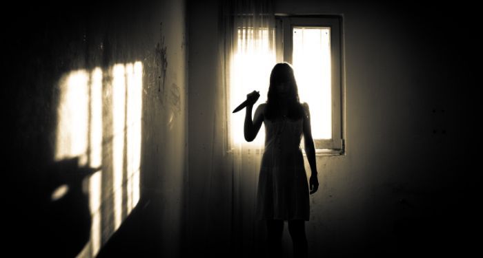 a woman in silhouette holding a knife in midair