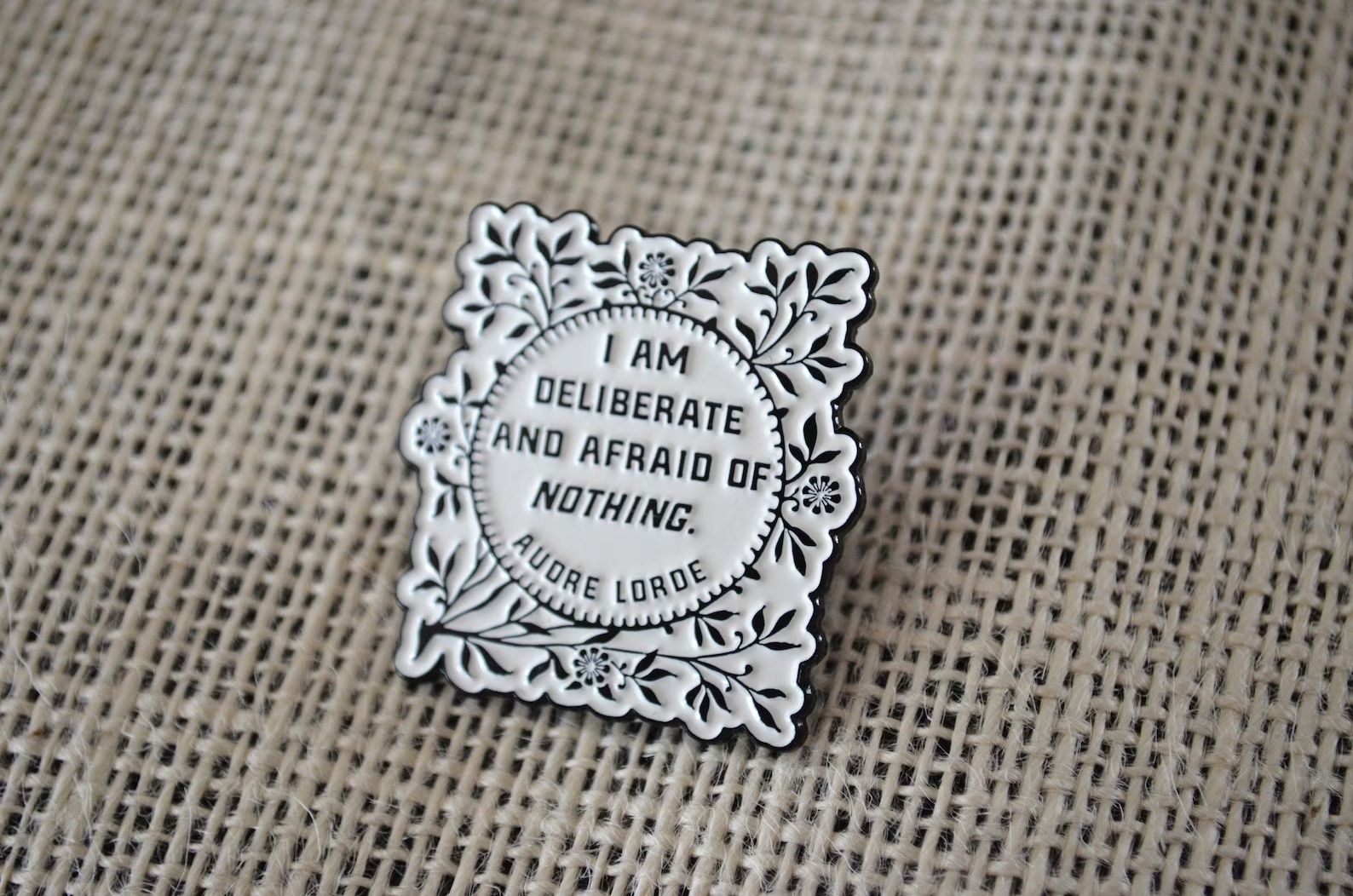 a photo of an enamel pin that says "I am deliberate and afraid of nothing."